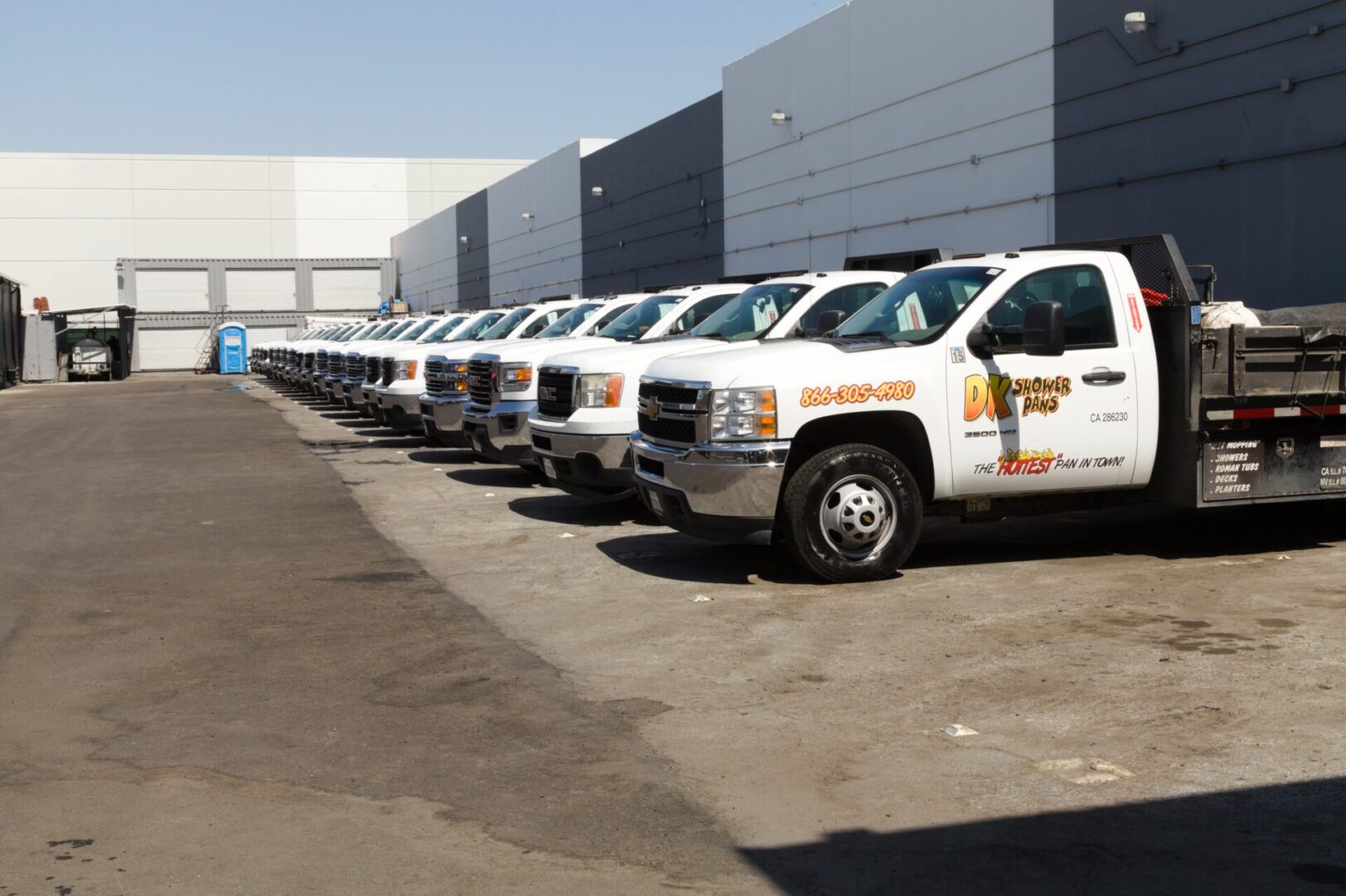 A row of white trucks parked in front of a building.